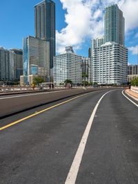 a very wide road next to a very tall building near the water with people walking on it