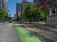 the green paint is painted on a bike path in front of an office building and large, trees