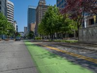 the green paint is painted on a bike path in front of an office building and large, trees