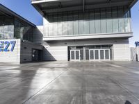 an empty building with many glass doors and large windows on it, sitting on cement