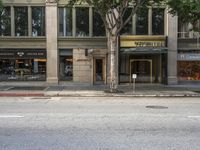 an entrance to an upscale city business on the street from across the street and an empty parking spot in front