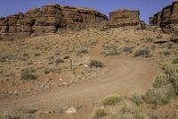 a person's shadow is shown on a path in the desert near red rock formations