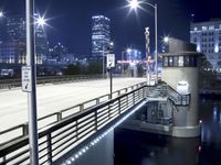 a bridge at night, lit up with street lamps, and a stoplight over the walkway