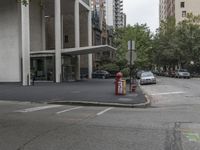 an empty street next to a parking lot with buildings and parked cars on the side of it