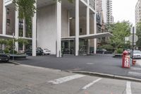 an empty street next to a parking lot with buildings and parked cars on the side of it
