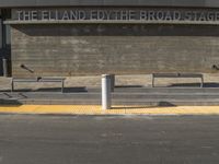 a parking space with two empty benches in front of it and a sign above it that reads the elland fox theatre