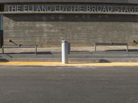 a parking space with two empty benches in front of it and a sign above it that reads the elland fox theatre