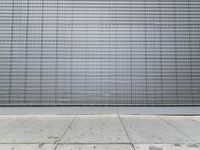 a tall building has metal sheets on the side, along with stone and concrete tiles on the floor