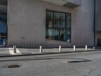 a street scene with a person riding on the sidewalk and a bike leaning against the building