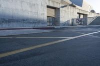 a building with a ramp over it in front of a road with yellow stripes on the street