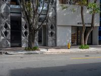 a white building with some trees in front of it with a yellow fire hydrant