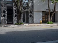 a white building with some trees in front of it with a yellow fire hydrant