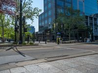 the green paint is painted on a bike path in front of an office building and large, trees