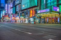 the corner of a street lined with tall buildings at night time with neon signs in the middle