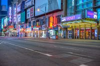 the corner of a street lined with tall buildings at night time with neon signs in the middle