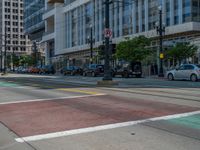 the green paint is painted on a bike path in front of an office building and large, trees