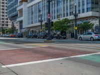 the green paint is painted on a bike path in front of an office building and large, trees