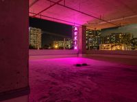 a rooftop parking garage with a bright neon sign above the garage floor, below an inner parking garage in a modern city with high rise to the skyscrapers