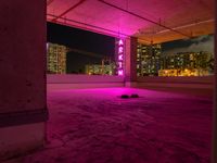 a rooftop parking garage with a bright neon sign above the garage floor, below an inner parking garage in a modern city with high rise to the skyscrapers