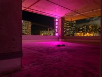 a rooftop parking garage with a bright neon sign above the garage floor, below an inner parking garage in a modern city with high rise to the skyscrapers