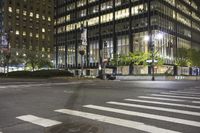 the view of a city with several tall buildings, street lights and people crossing a crosswalk