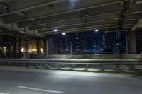 the city lights are on at night from a highway above the road from inside an overpass