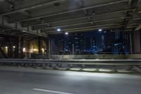 the city lights are on at night from a highway above the road from inside an overpass