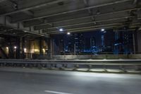 the city lights are on at night from a highway above the road from inside an overpass