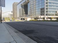 a city street lined with tall glassy buildings and trees with people crossing on the sidewalk