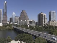 an overpass with many tall buildings and cars driving on it and a river that runs along the sides of the road