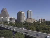 an overpass with many tall buildings and cars driving on it and a river that runs along the sides of the road
