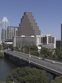 an overpass with many tall buildings and cars driving on it and a river that runs along the sides of the road
