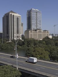 an overpass with many tall buildings and cars driving on it and a river that runs along the sides of the road