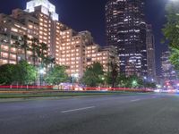 an empty city street in front of a tall office building at night with many lights