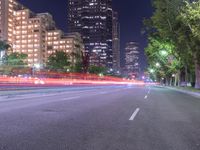 an empty city street in front of a tall office building at night with many lights