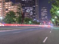 an empty city street in front of a tall office building at night with many lights