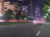 an empty city street in front of a tall office building at night with many lights