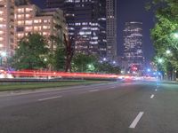 an empty city street in front of a tall office building at night with many lights