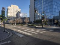 a empty city street at an intersection with buildings behind it and blue skies reflecting off the windows