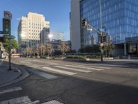 a empty city street at an intersection with buildings behind it and blue skies reflecting off the windows