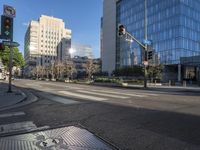 a empty city street at an intersection with buildings behind it and blue skies reflecting off the windows