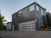 a big garage building that has a large window on it that is located off of the driveway