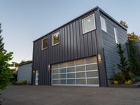 a big garage building that has a large window on it that is located off of the driveway