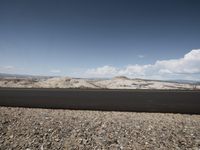 a road in the desert, with a white car driving down the street next to it