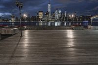 a view of new york city skyline at night from pier on the hudson river side