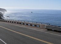 a scenic highway in front of the ocean and a cliff side area with yellow lines on it