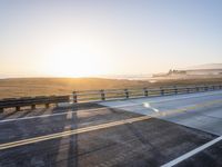 a sunset view from the road showing an empty roadway with yellow lines and some hills