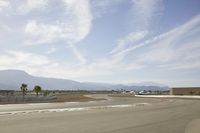 the asphalt surface of an airport runway with mountains in the background and sun rays in the air