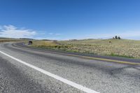 two lines on the road on a sunny day in wyoming, usa, with a black truck at left, and mountain scene behind