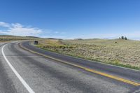 two lines on the road on a sunny day in wyoming, usa, with a black truck at left, and mountain scene behind